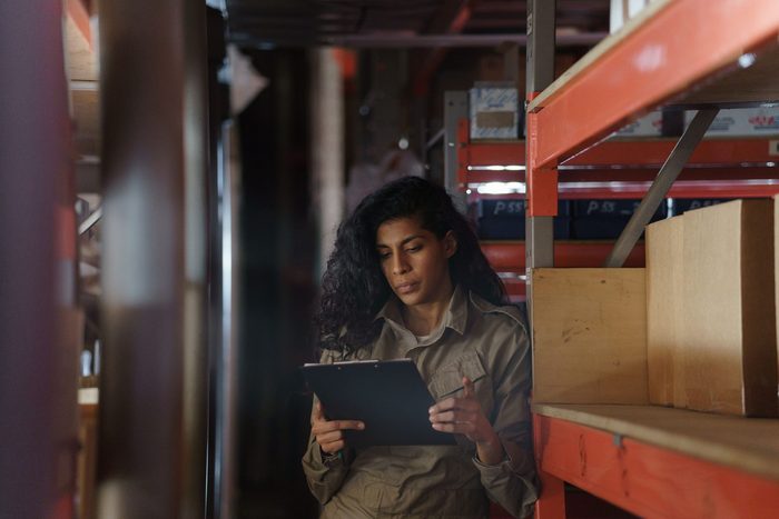 Profissional a consultar um tablet num corredor de armazém